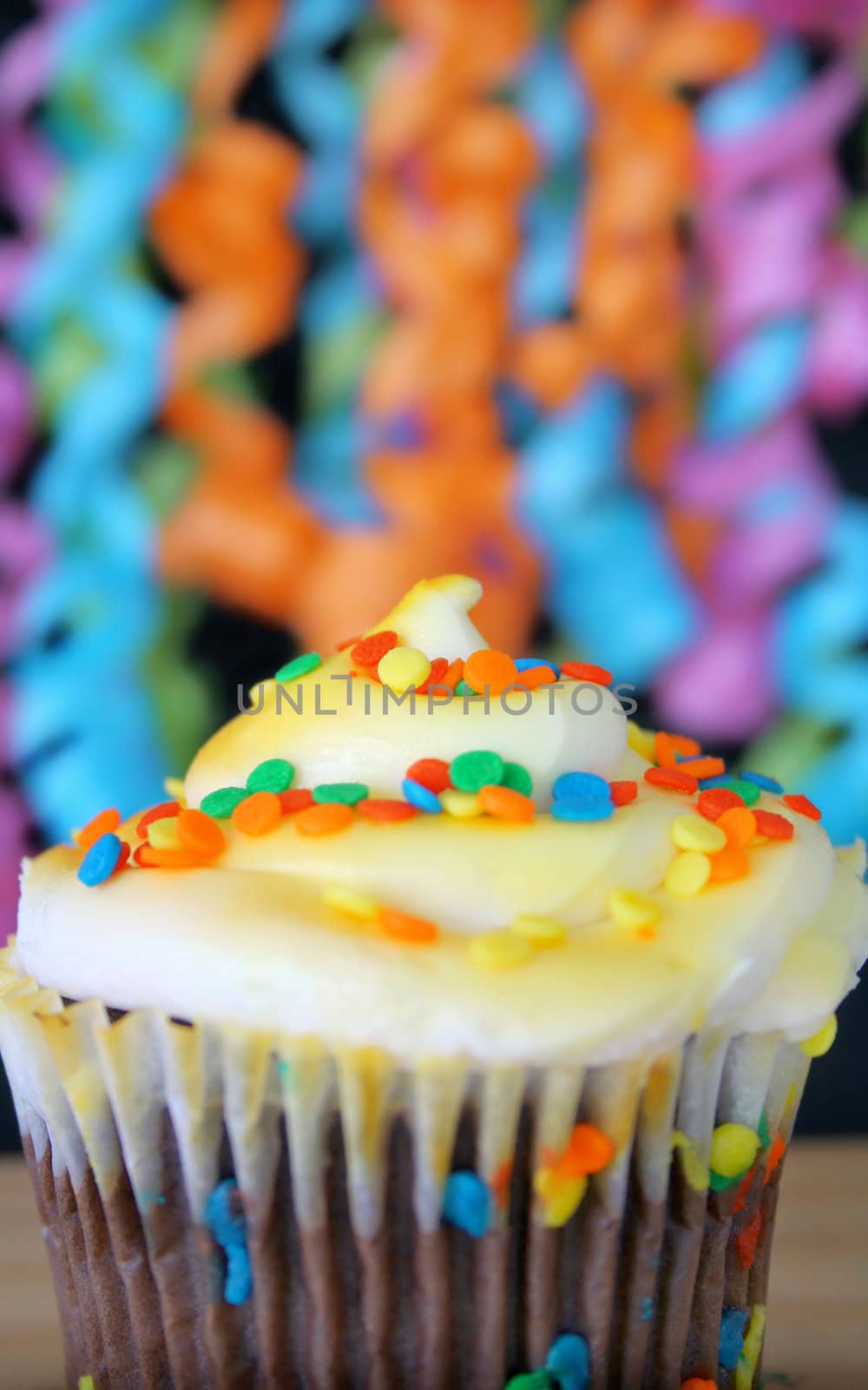 One cupcake with sprinkles and ribbons hanging in the background.  Used a shallow depth of field and selective focus on the middle part of cupcake and sprinkles.