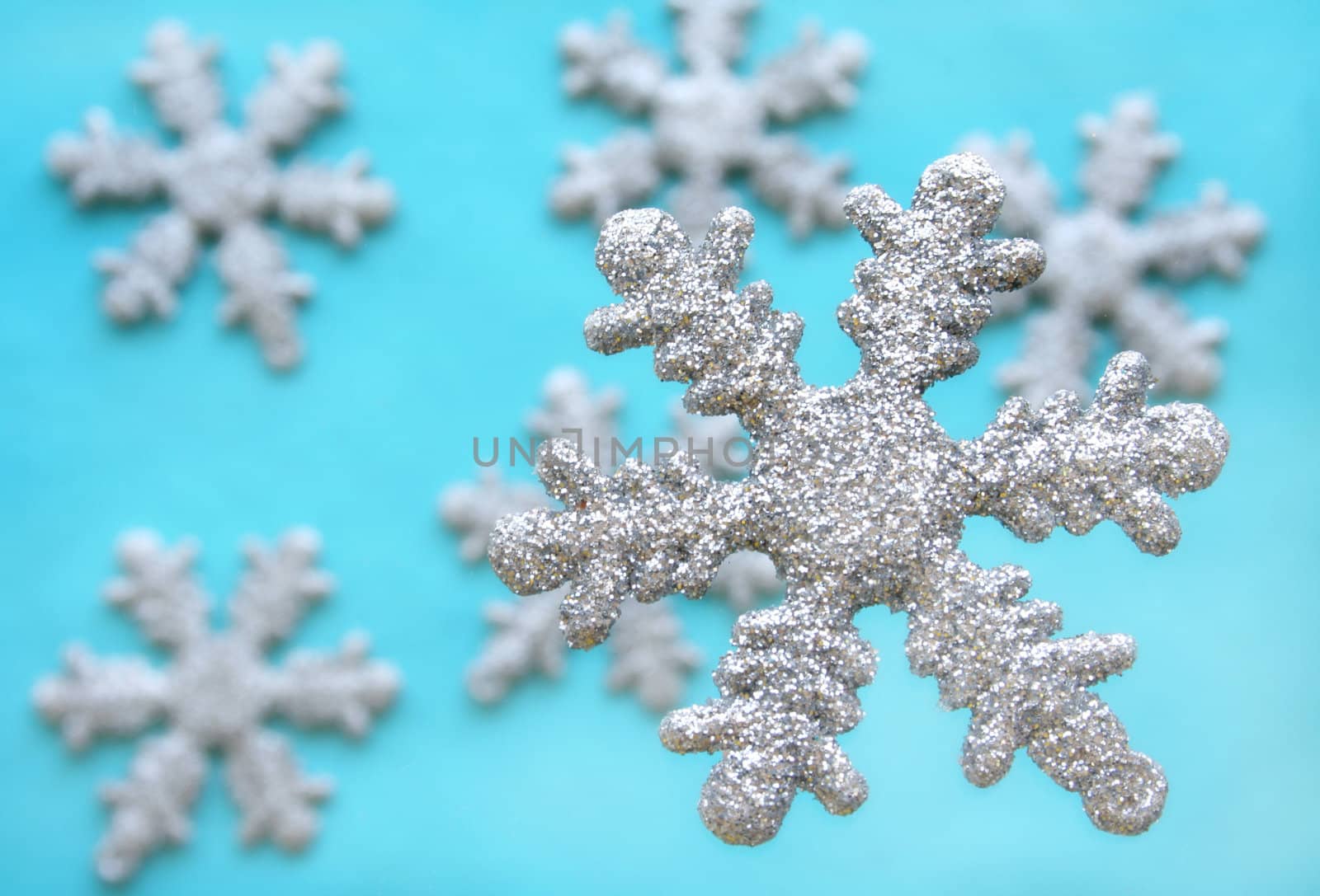 Snow flakes covered in silver glitter with a blue background.  Used a shallow depth of field and a soft focus filter to add to the fantasy feeling of the image.