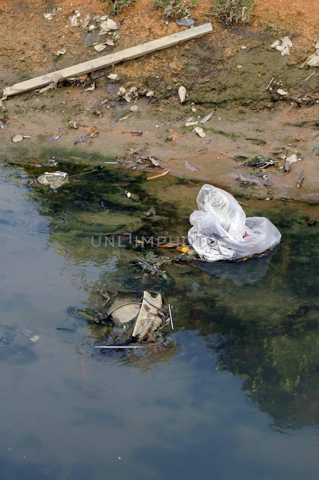 Dirty river pollution with plastic bag and toxic waste. Please care for the environment