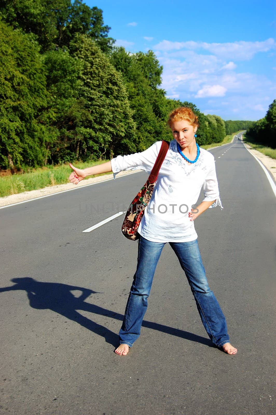 girl hitchhiking on road under blues sky