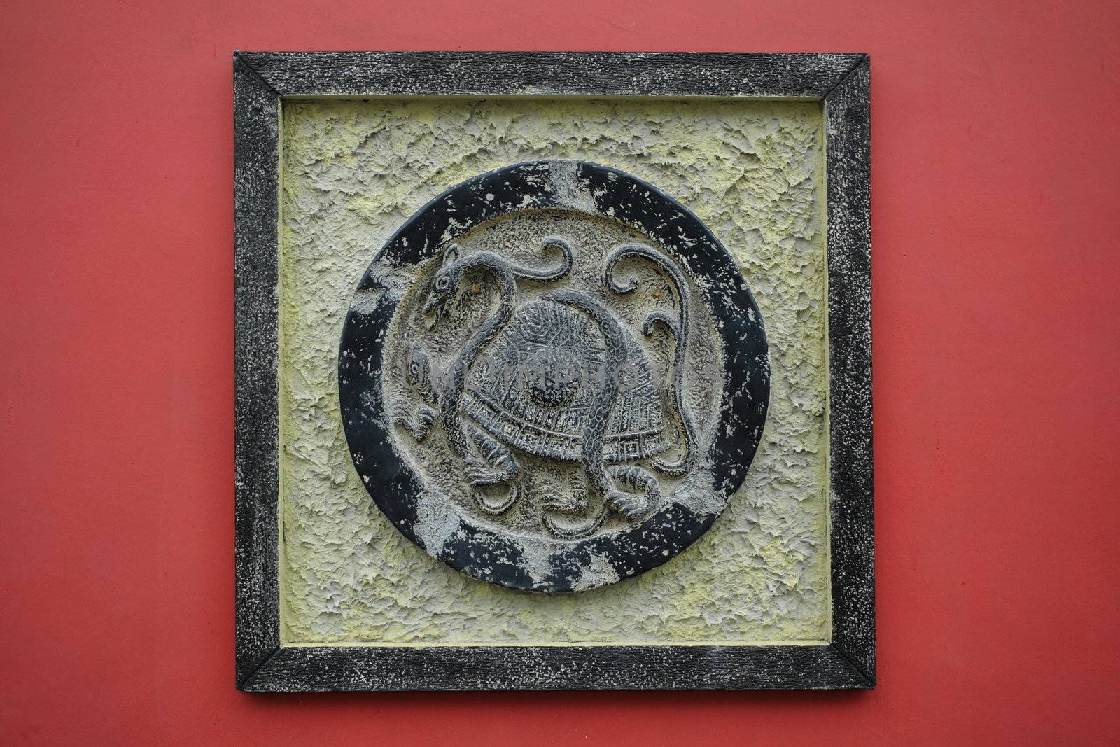 bronze "Black Tortoise" sculpture on a red wall by leungchopan