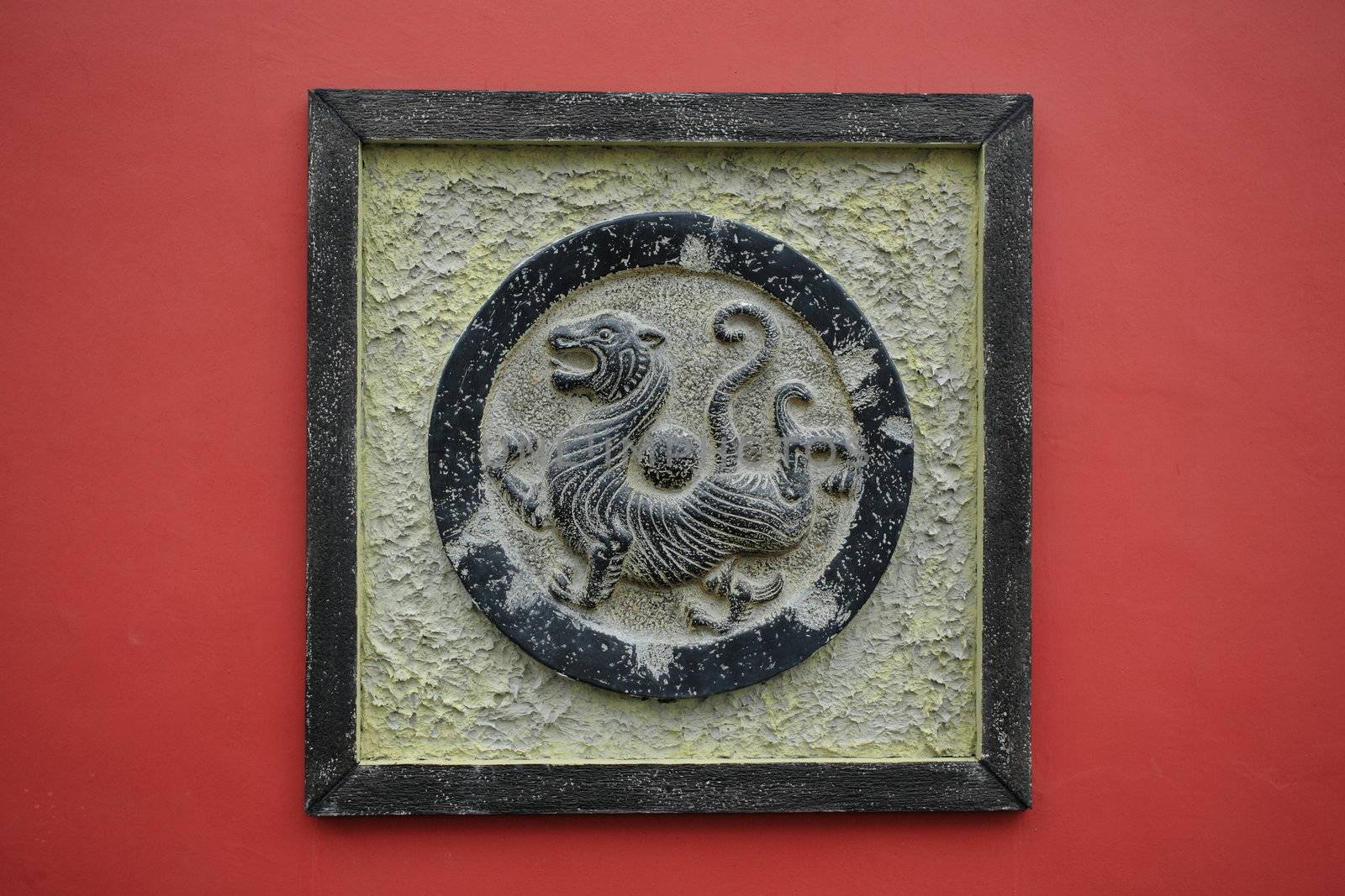 bronze tiger sculpture on a red wall