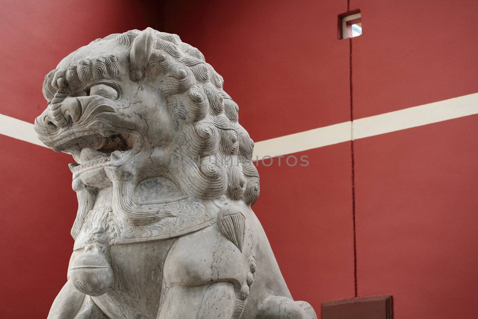stone lion statue before the red wall by leungchopan