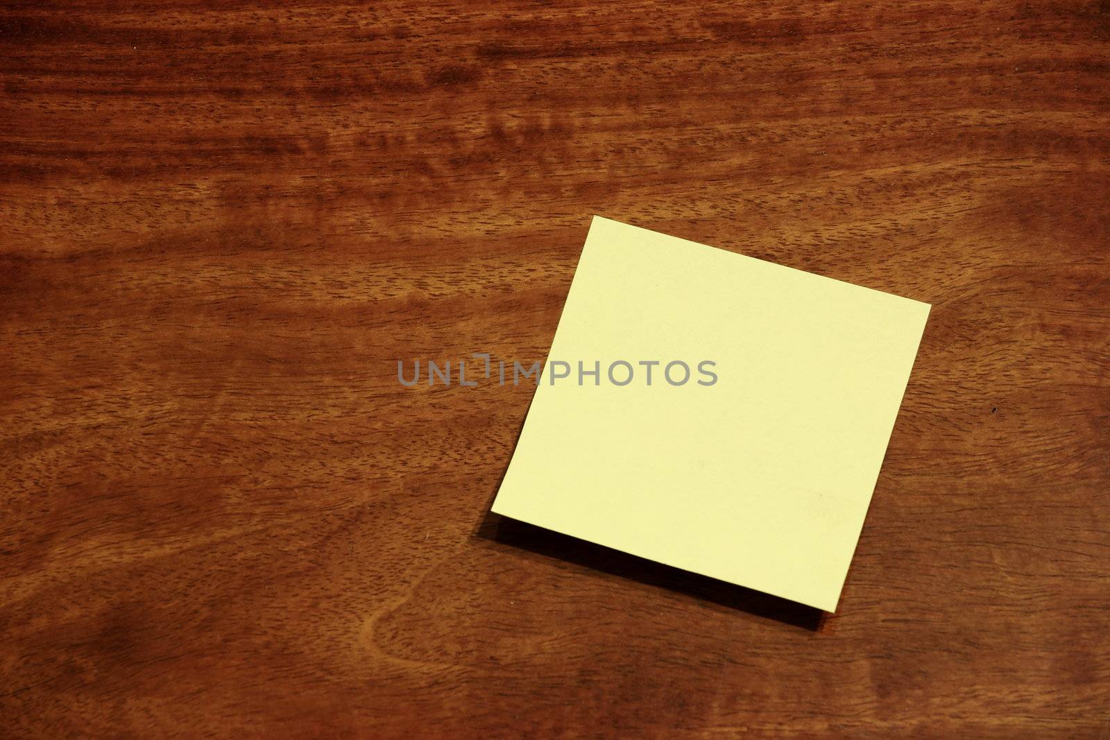 Yellow sticky memo note on wooden background by leungchopan