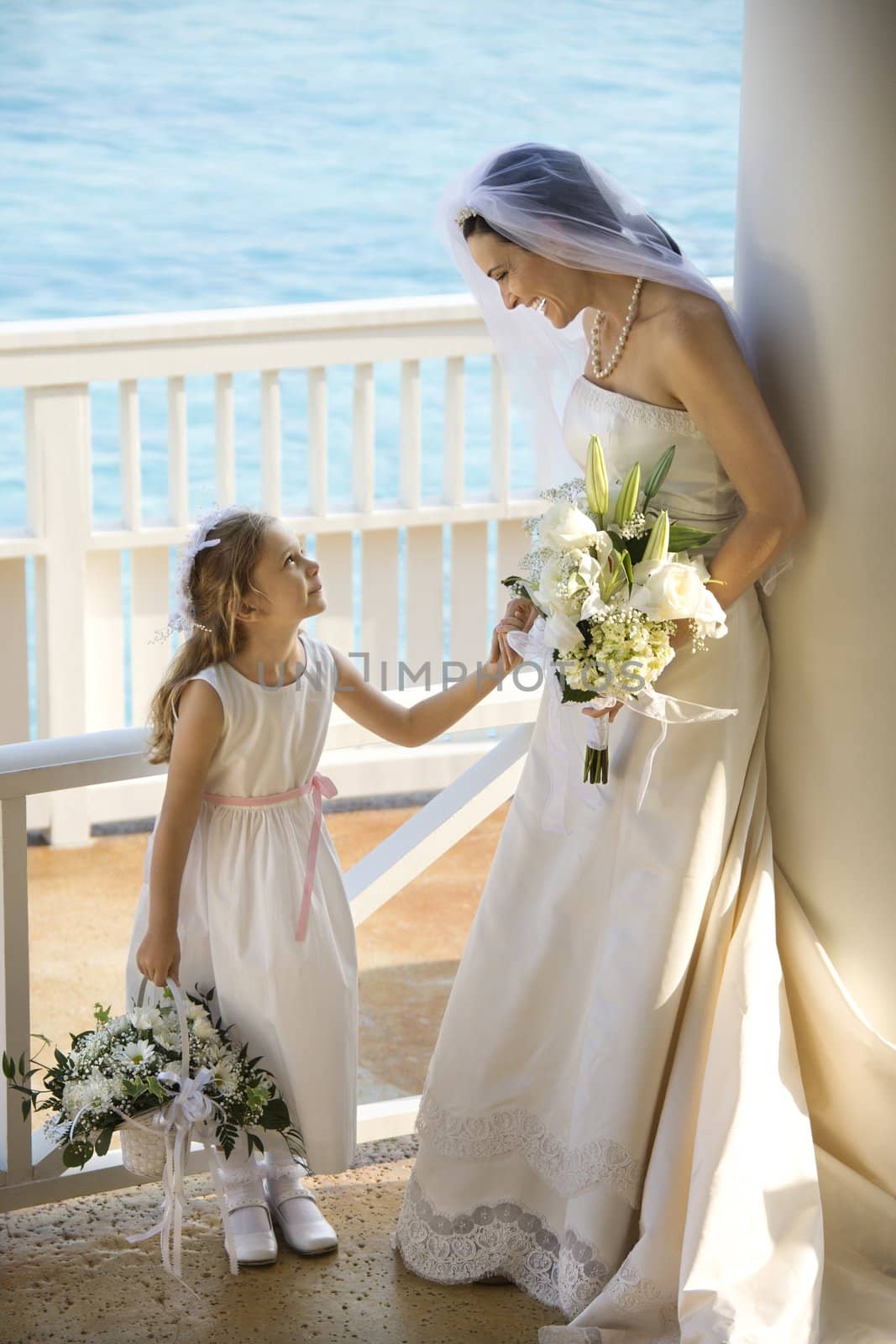 Caucasian mid-adult bride holding hands with flower girl.