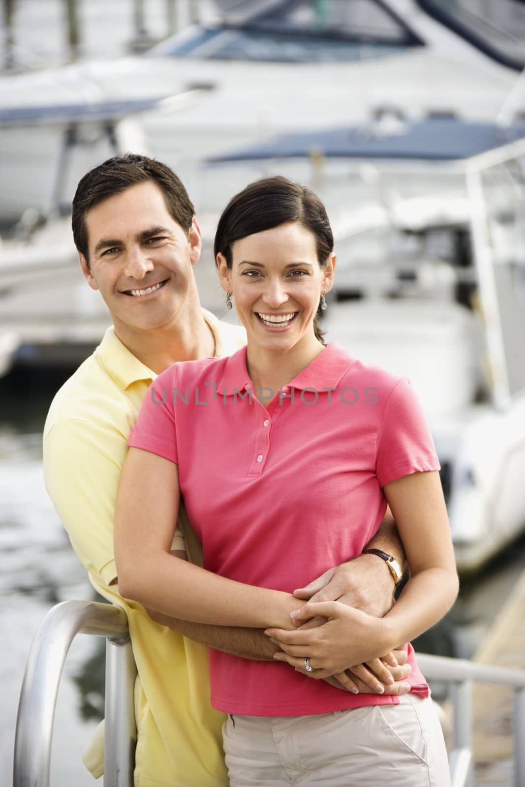 Portrait of Caucasian mid-adult couple embracing at harbor.