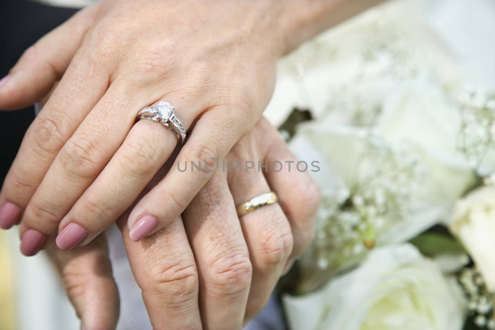 Close-up of bride and groom's hands overlapping.