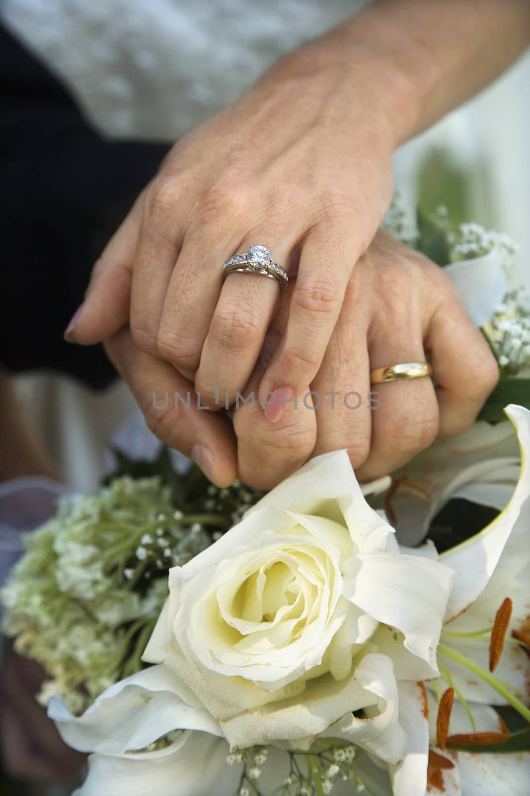Close up image of bride and groom's hands overlapping.