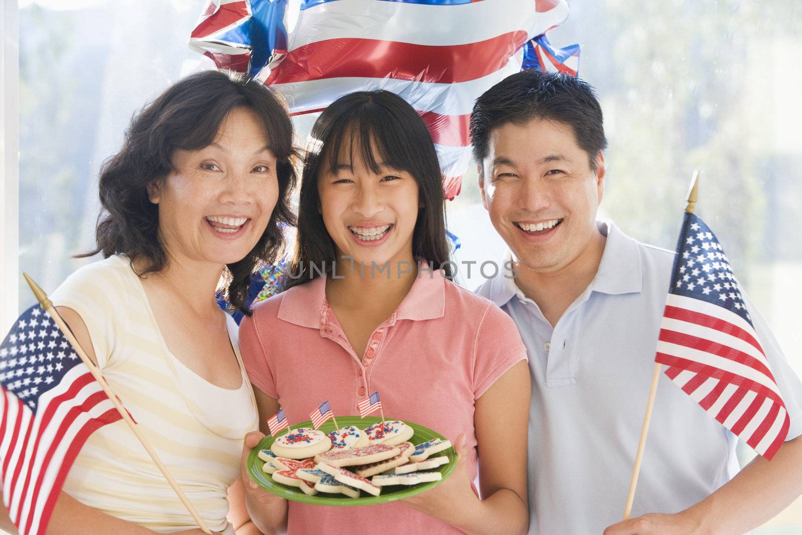 Family outdoors on fourth of July with flags and cookies smiling by MonkeyBusiness