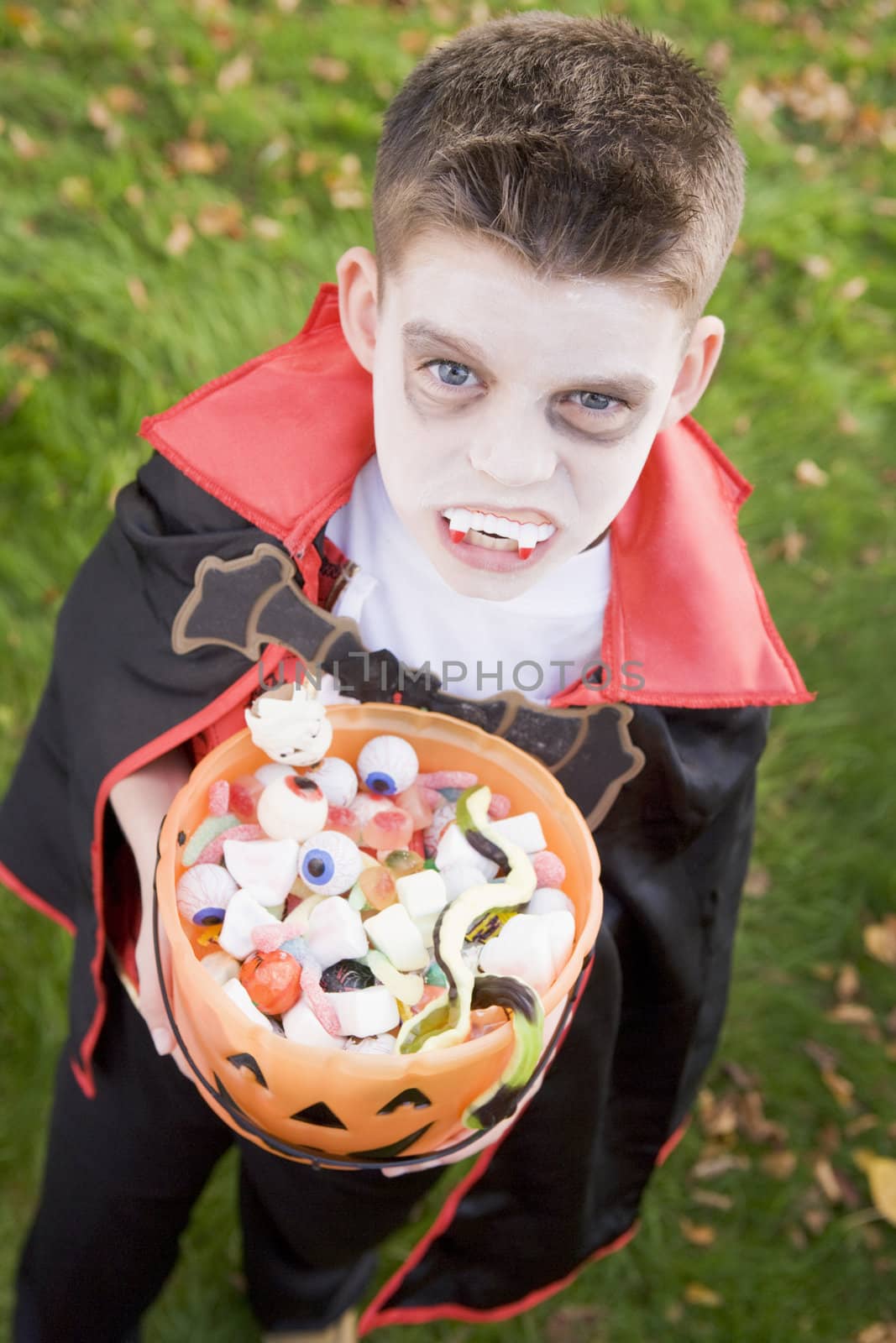 Young boy outdoors wearing vampire costume on Halloween holding  by MonkeyBusiness