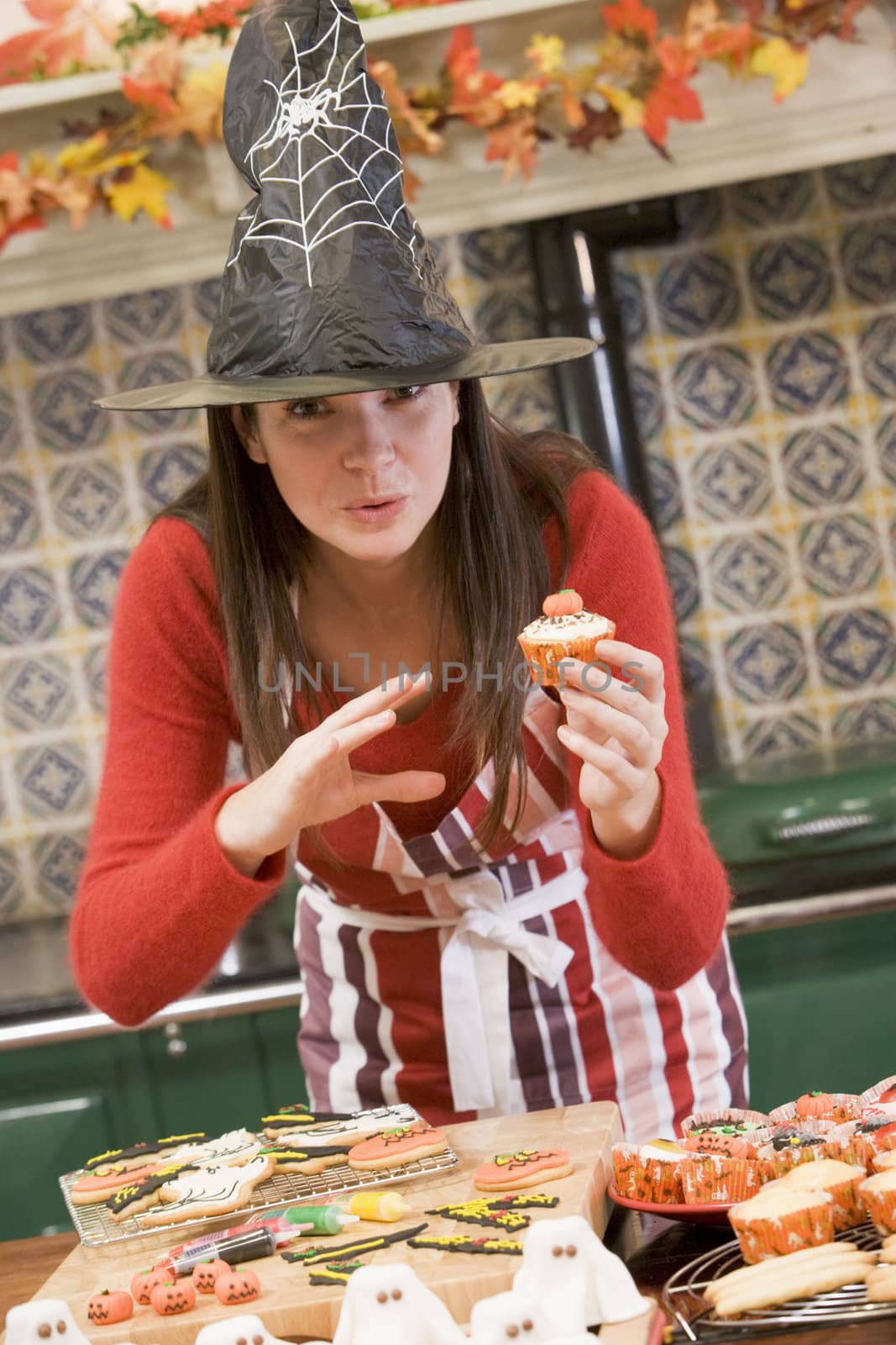 Woman in kitchen making Halloween treats and smiling by MonkeyBusiness