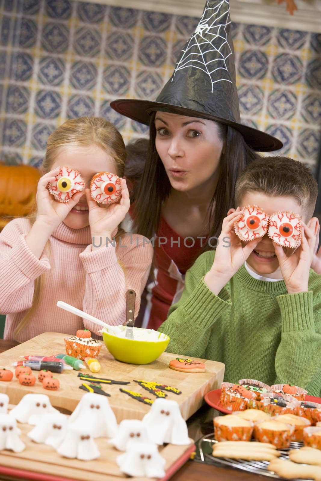 Mother and two children at Halloween playing with treats and smi by MonkeyBusiness