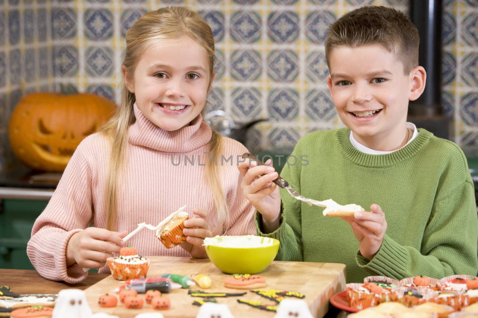 Brother and sister at Halloween making treats and smiling by MonkeyBusiness