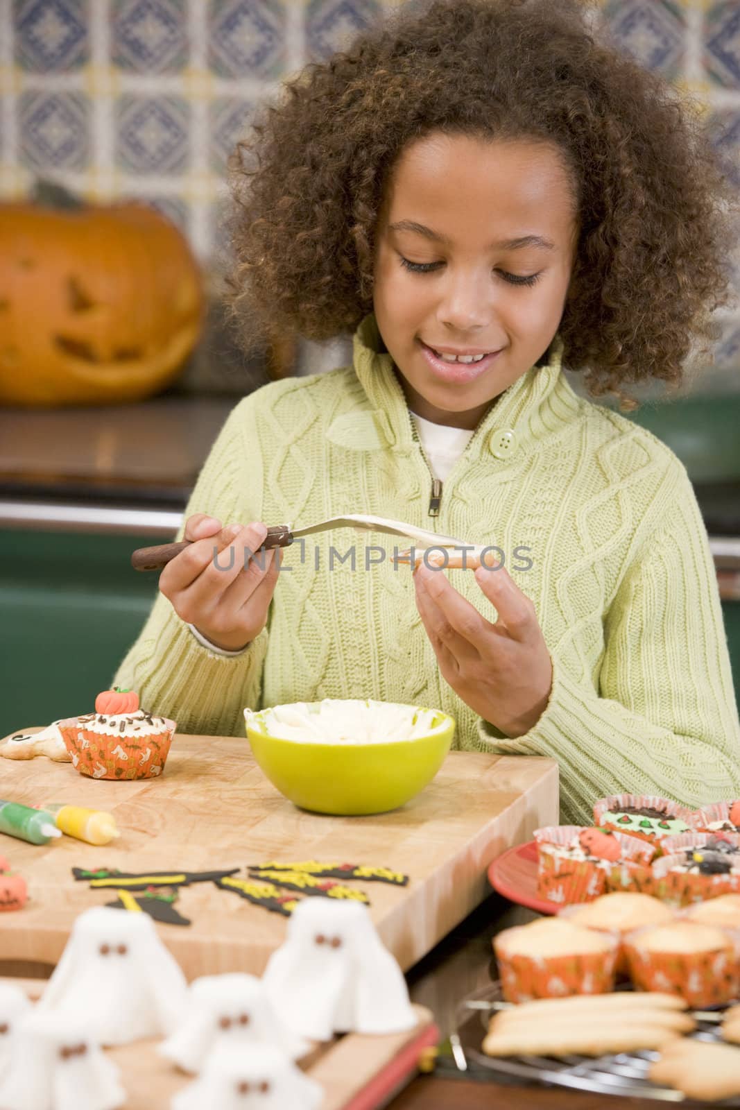 Young girl at Halloween making treats and smiling by MonkeyBusiness