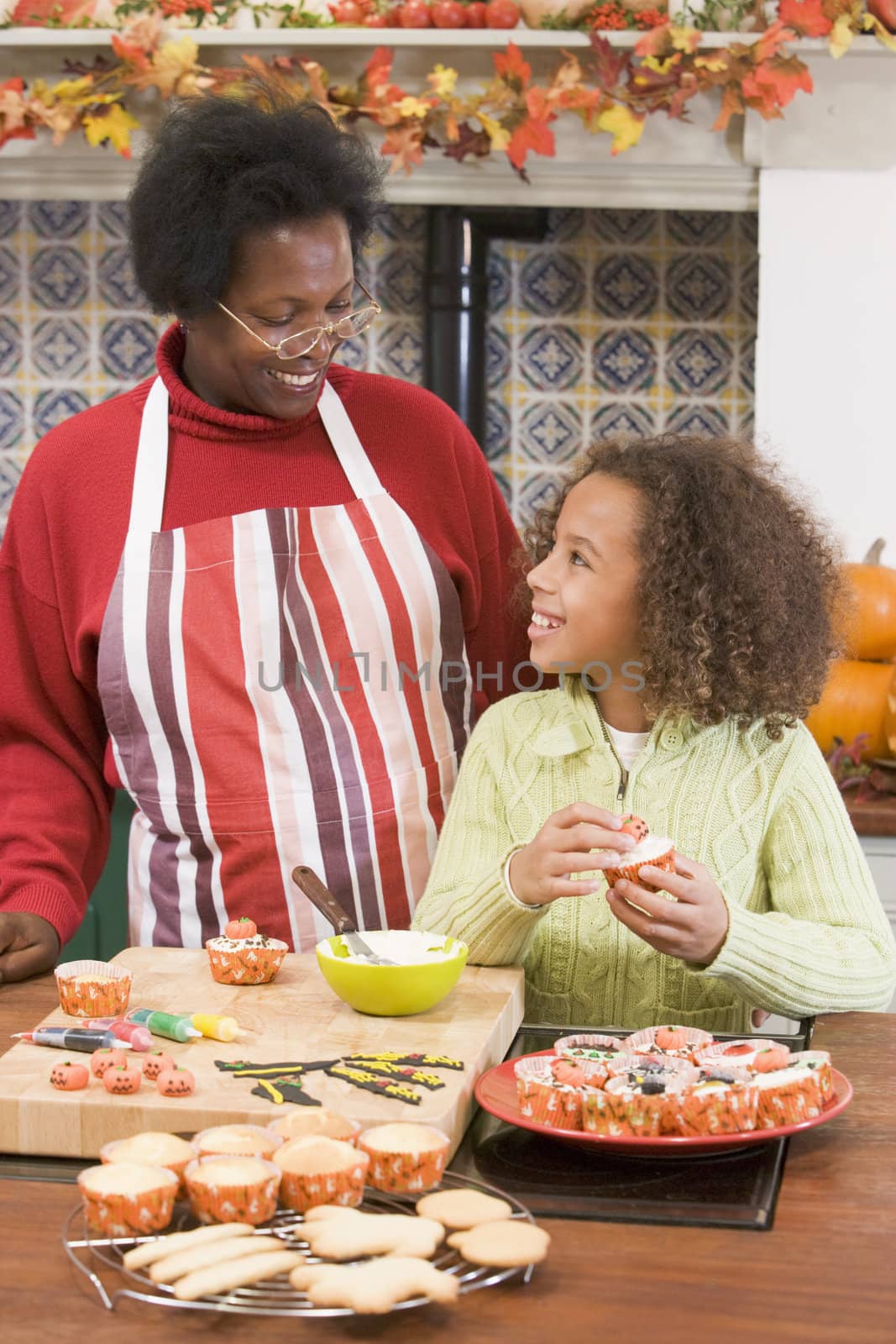 Grandmother and granddaughter making Halloween treats and smilin by MonkeyBusiness