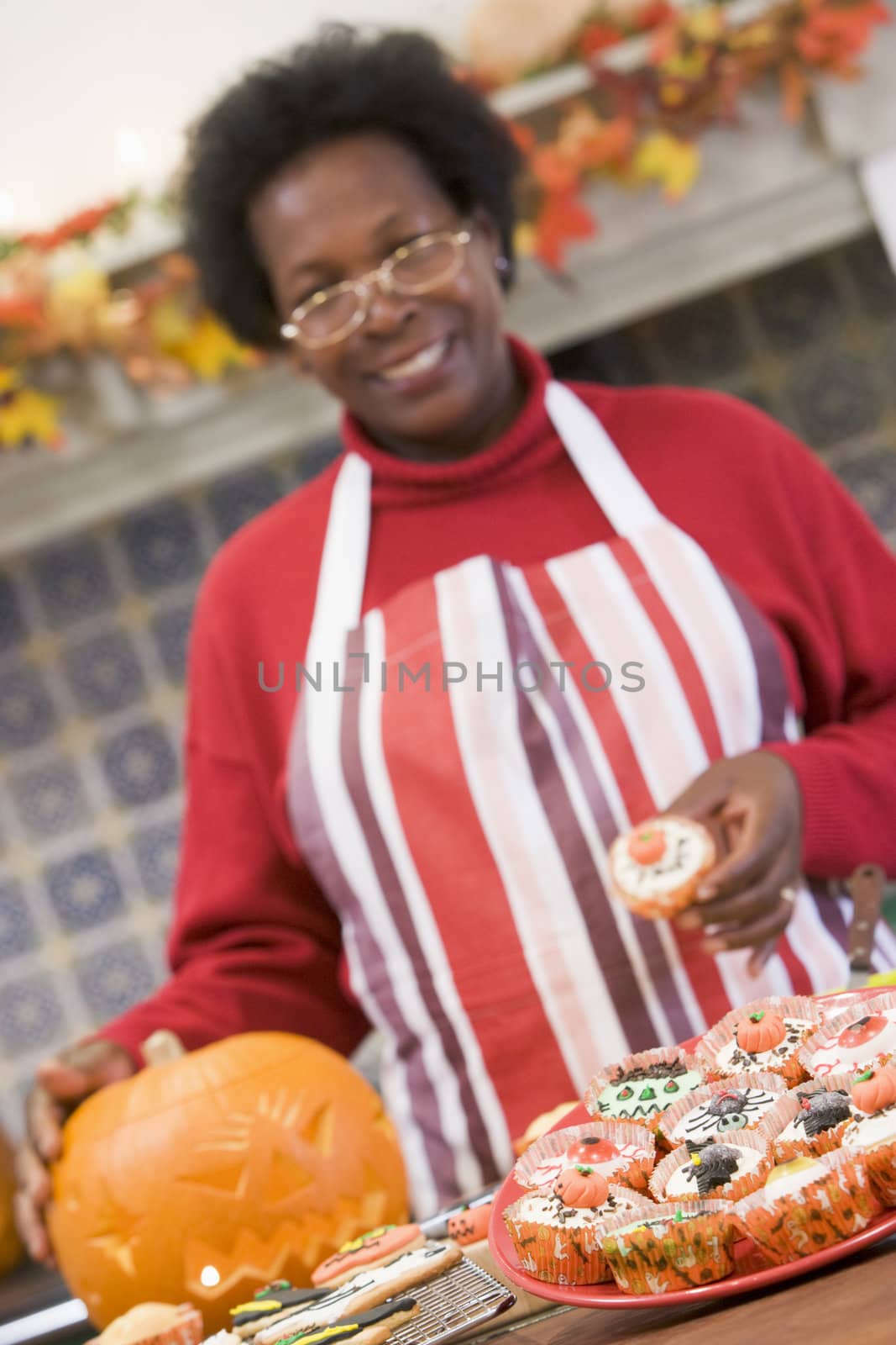 Woman in kitchen making Halloween treats and smiling by MonkeyBusiness