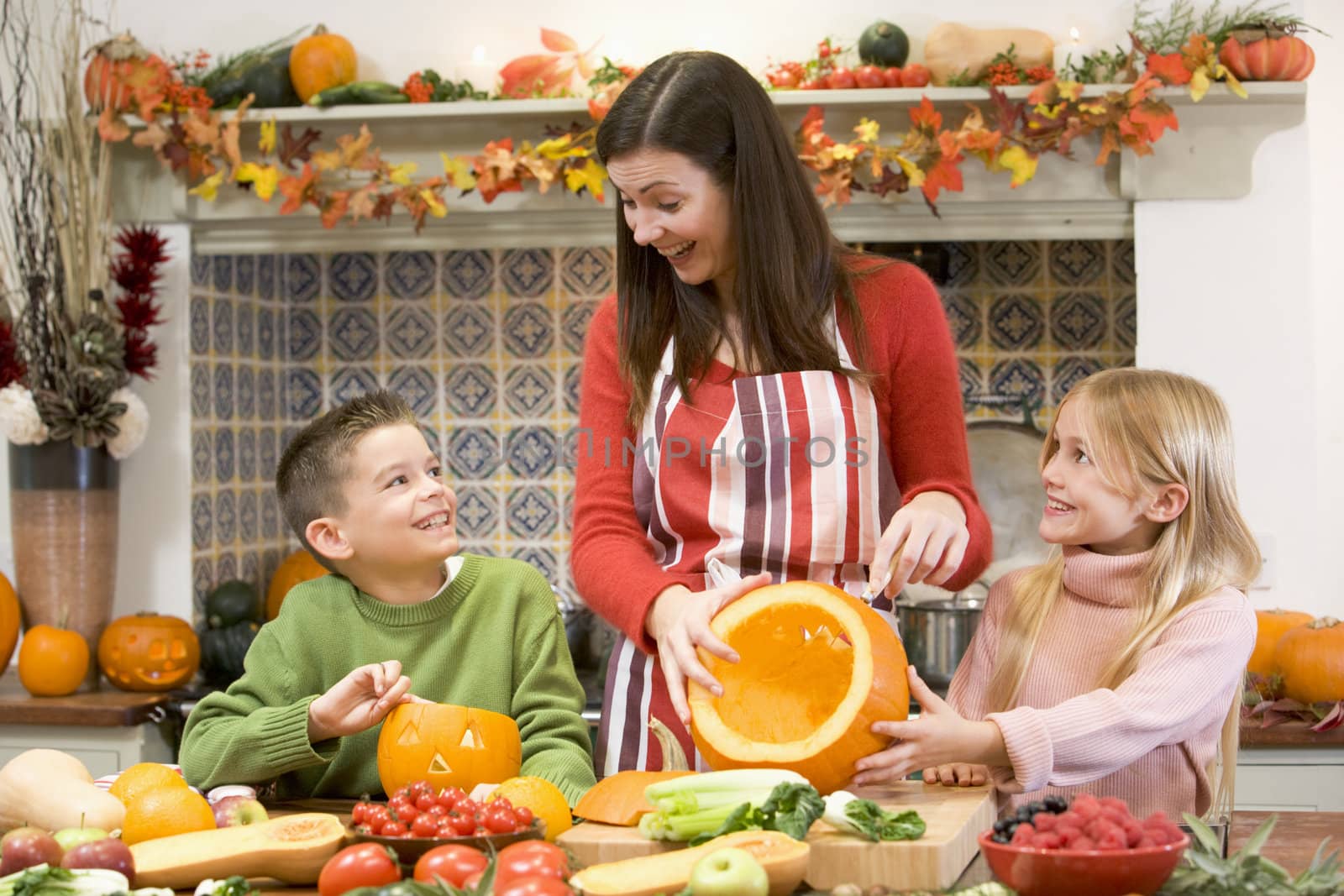 Mother and two children carving jack o lanterns on Halloween and by MonkeyBusiness