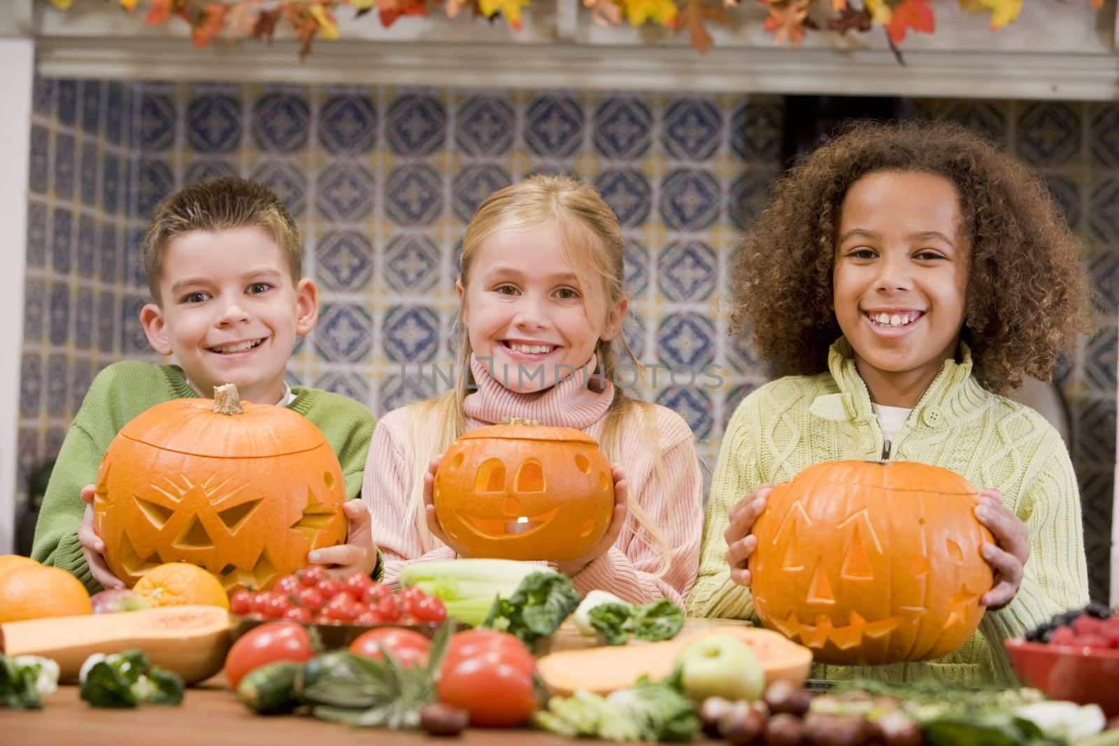 Three young friends on Halloween with jack o lanterns and food s by MonkeyBusiness