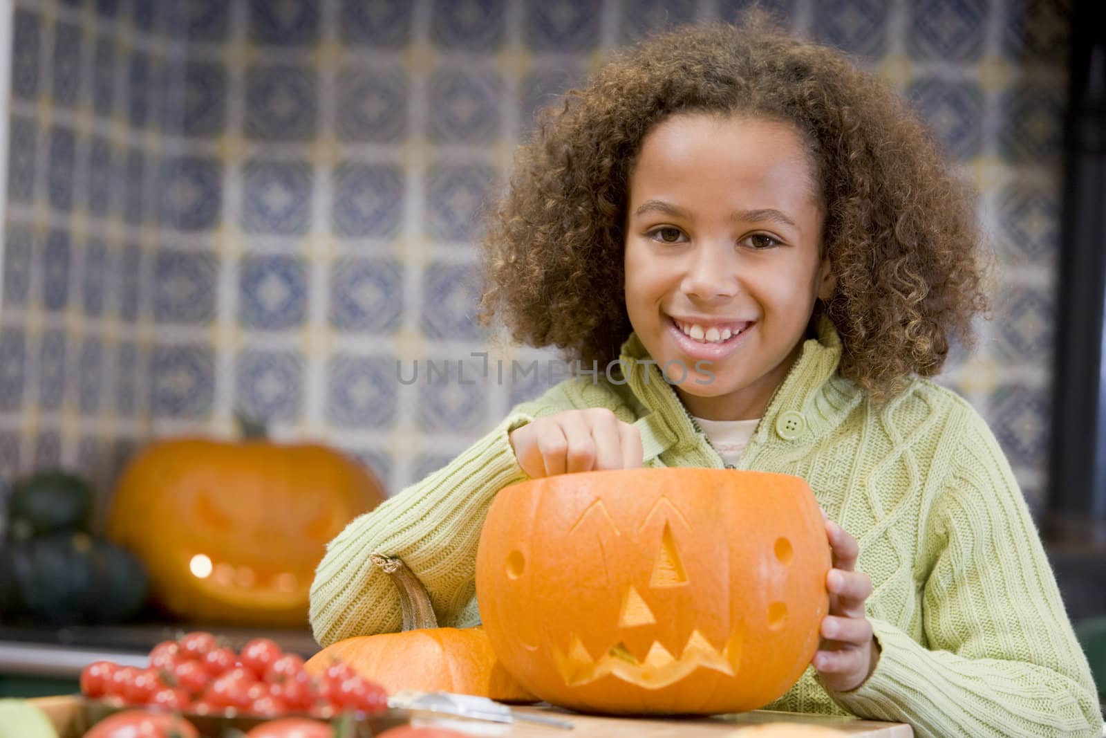 Young girl on Halloween with jack o lantern smiling by MonkeyBusiness