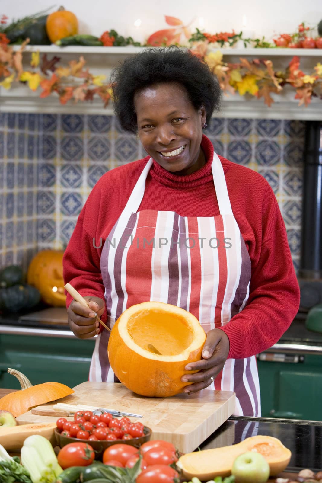 Woman on Halloween making jack o lantern smiling by MonkeyBusiness