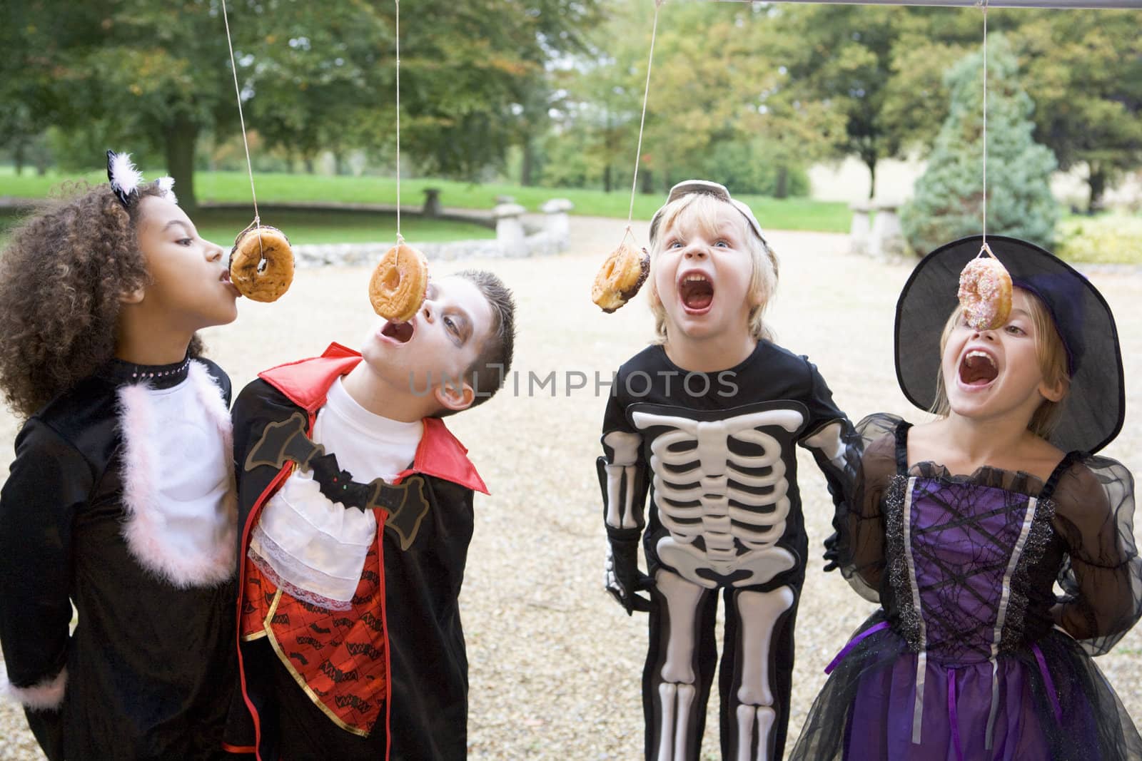 Four young friends on Halloween in costumes eating donuts hangin by MonkeyBusiness