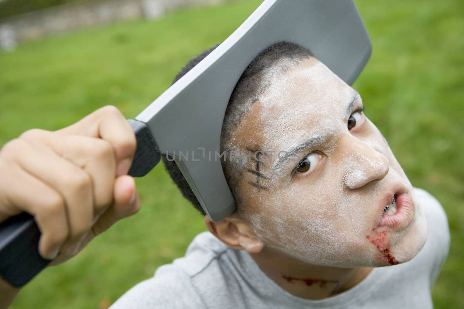 Young boy with scary Halloween make up and plastic knife through by MonkeyBusiness