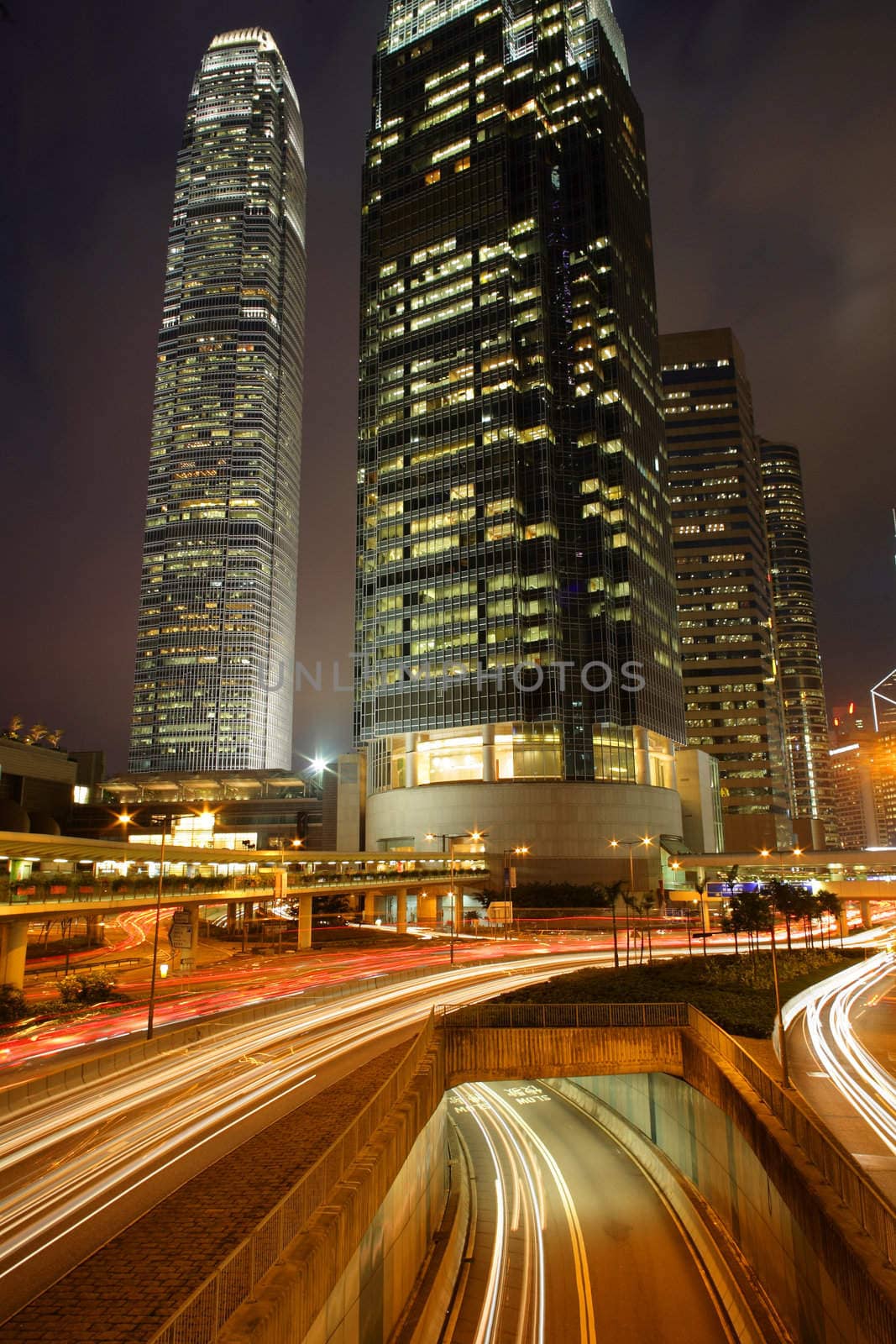 Night view of IFC (International Financial Centre) in Hong Kong with curving traffic light track.