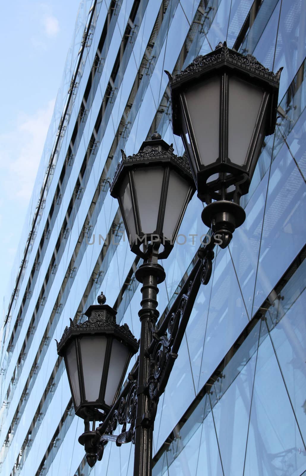 Old street lamp in front of modern buildings.