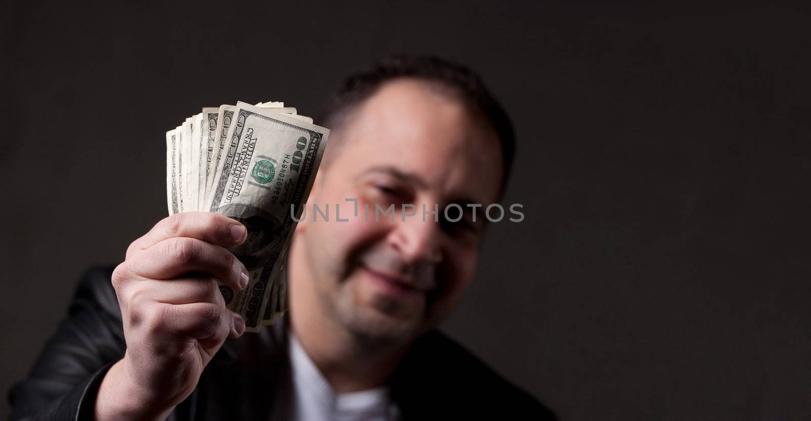 A happy middle aged man holding a handful of money with copyspace.