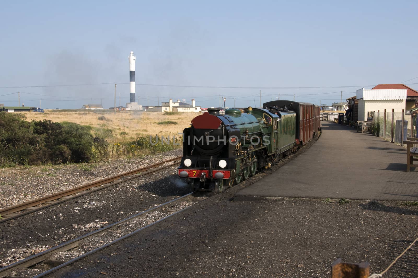 A miniature steam train with a lighthouse in the background