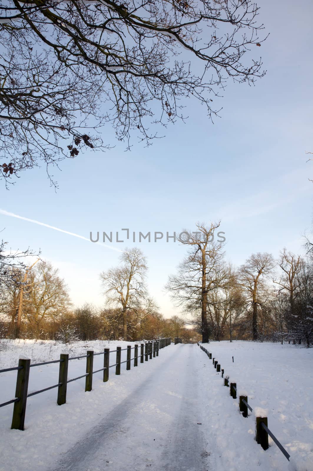 A footpath covered in snow with a fence