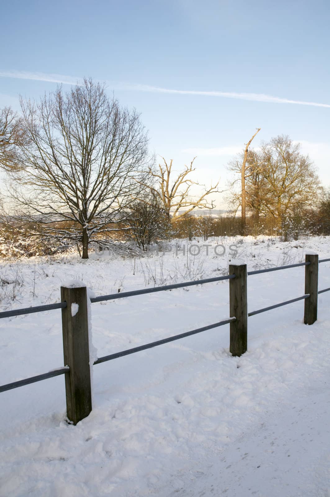 A footpath covered in snow with a fence