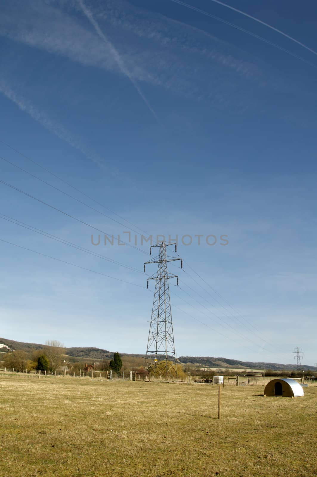 An electrical pylon in a field with a blue sky