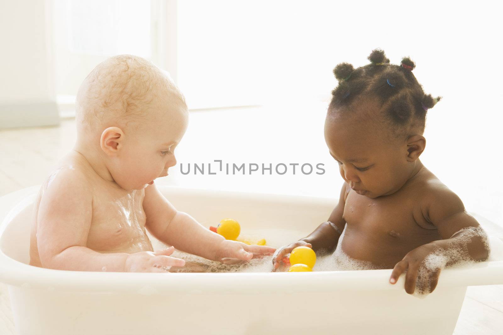 Two babies in bubble bath by MonkeyBusiness