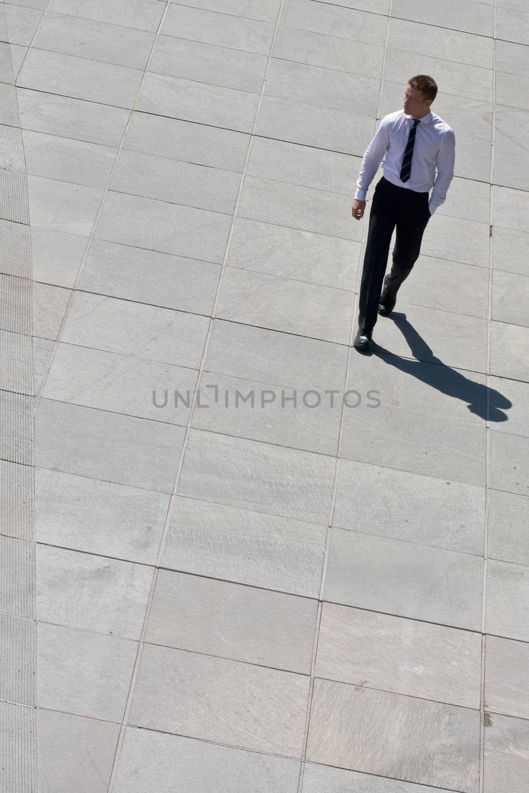 Young Corporate Man Walking On Pavement With His Hand In His Pocket
