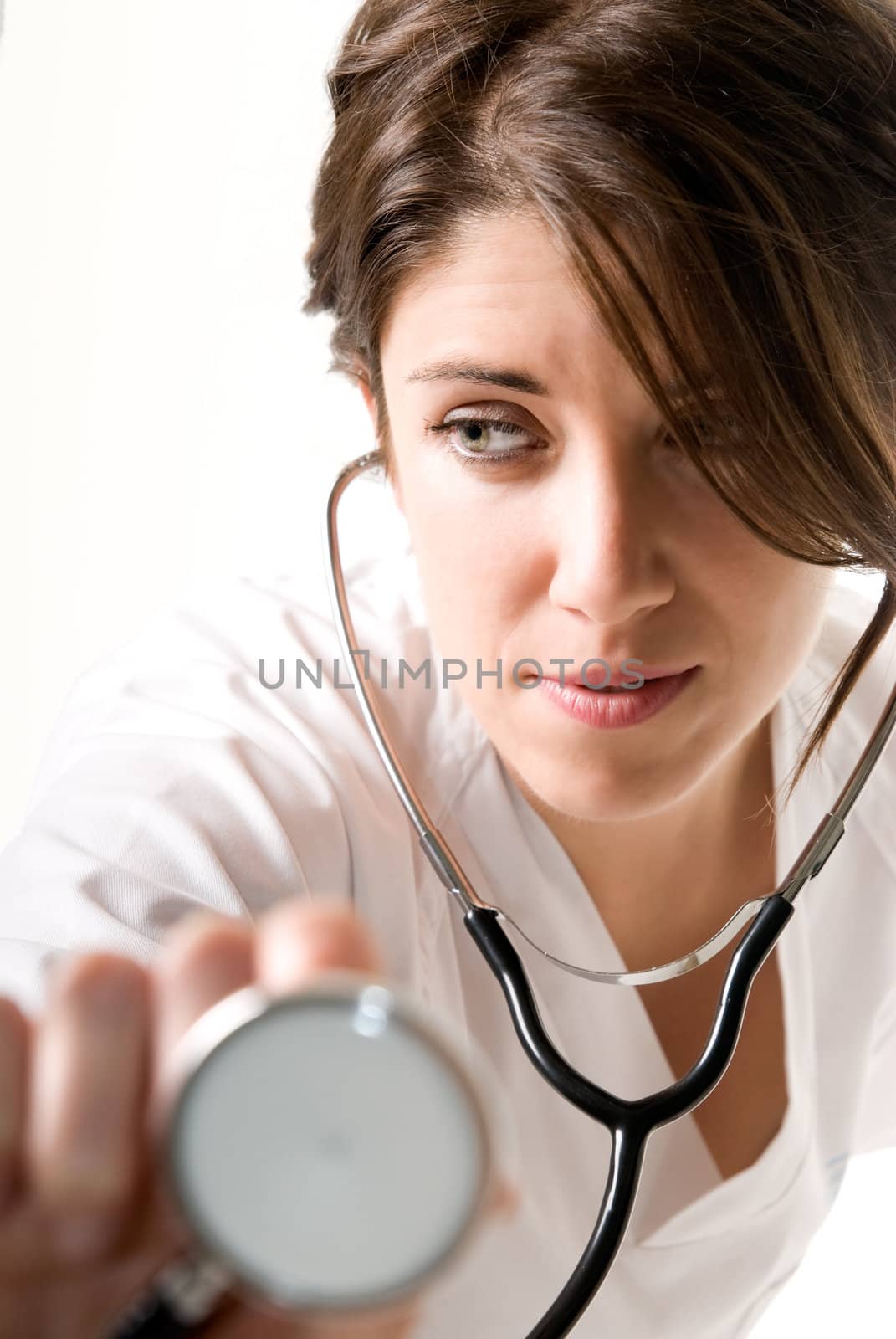 Young woman doctor with stethoscope on white background. Focused on face.