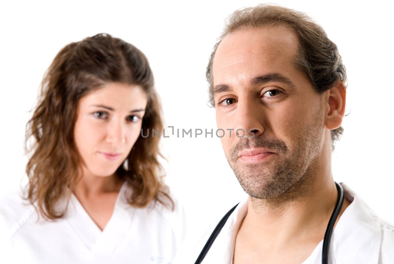 Adult doctor and young nurse on white background. Focused on doctor. 