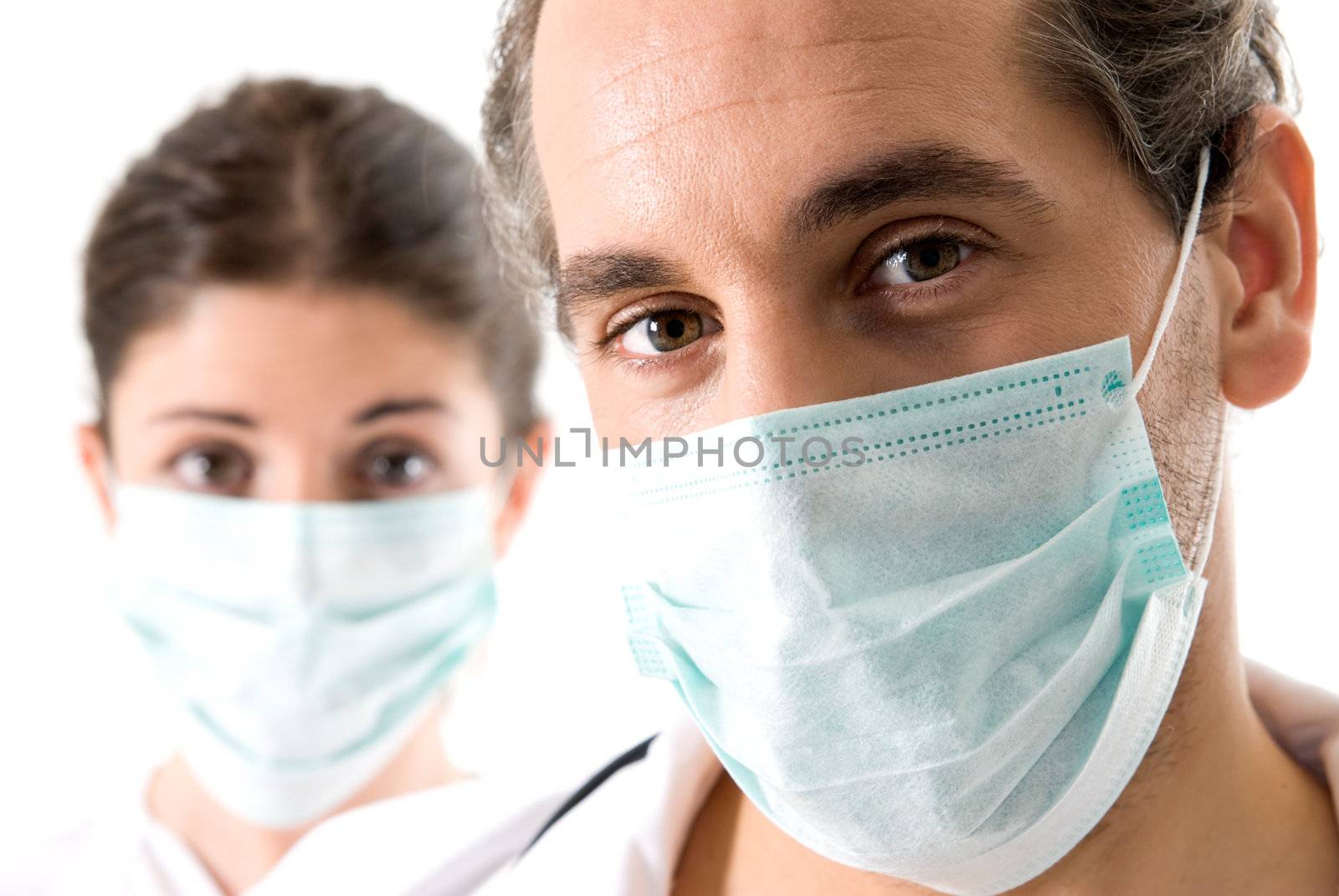 Adult doctor and young nurse with mask on white backgrund, focused on doctor. 