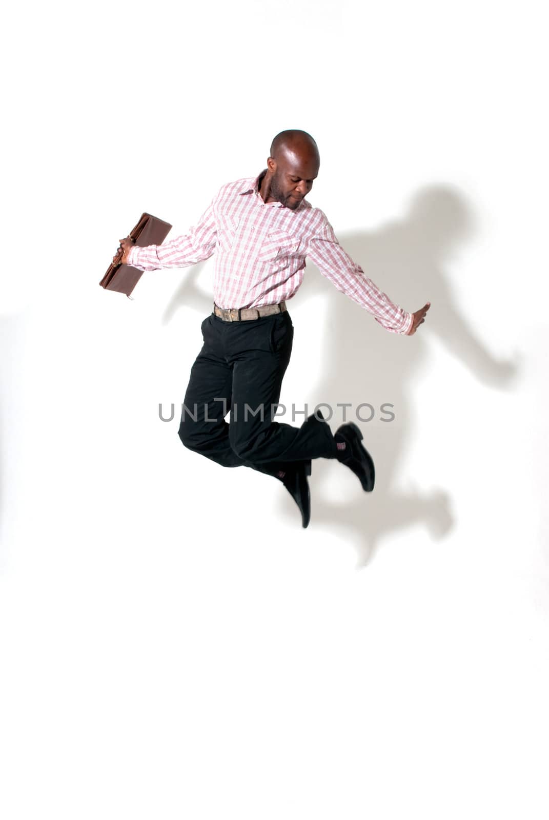 Happy african businessman smiling with briefcase jumping with shadow. 