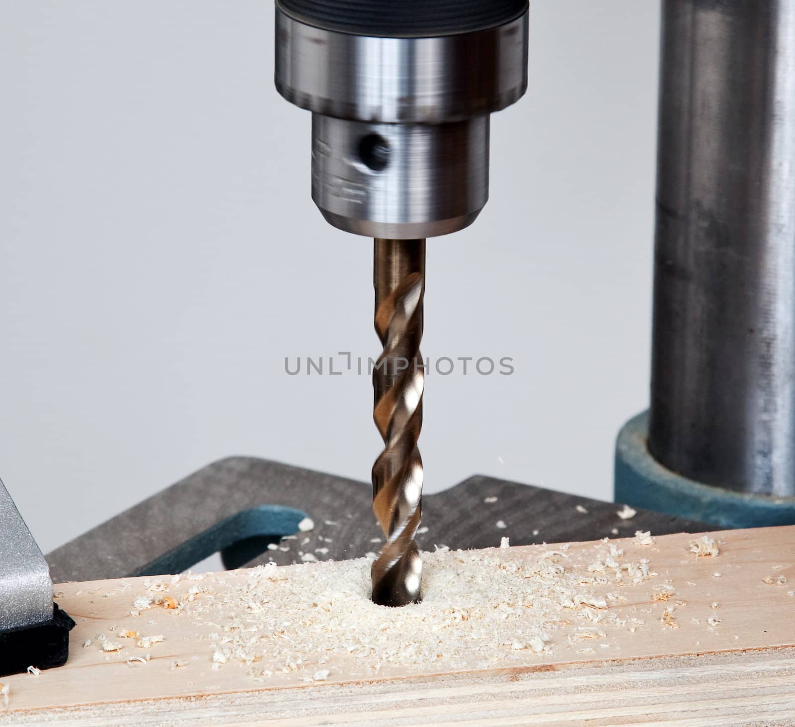 Large sized drill in solid chuck drilling deep into wood and throwing shavings about the surface