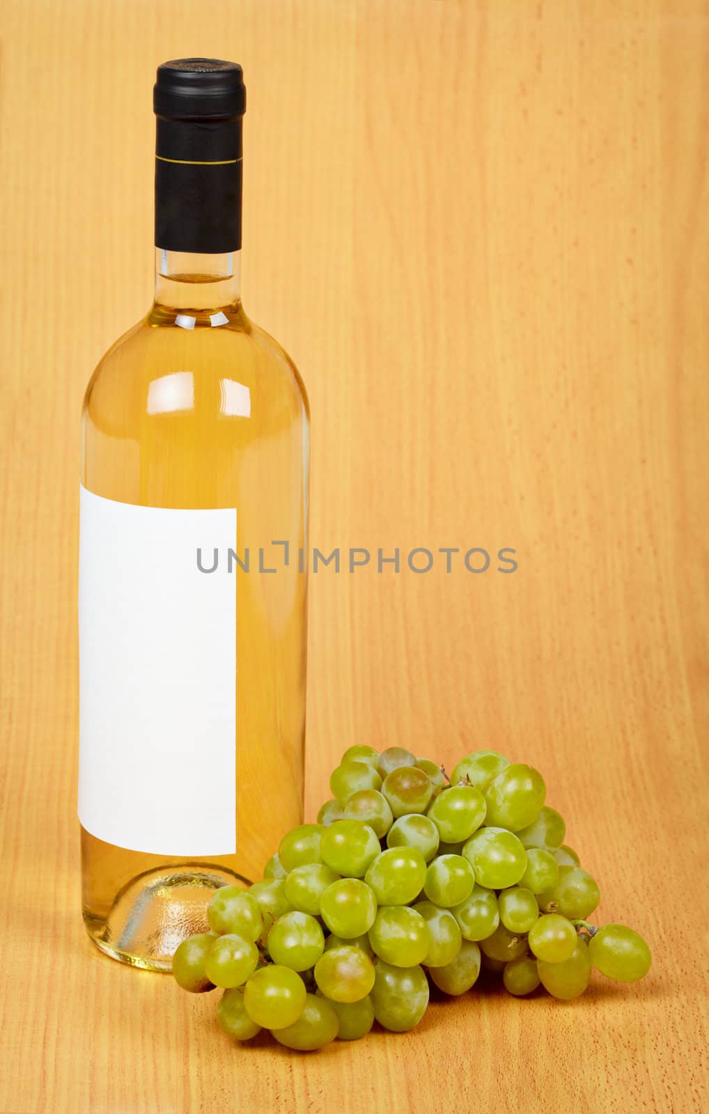 Still life - a bottle of white wine and grapes on a wooden surface