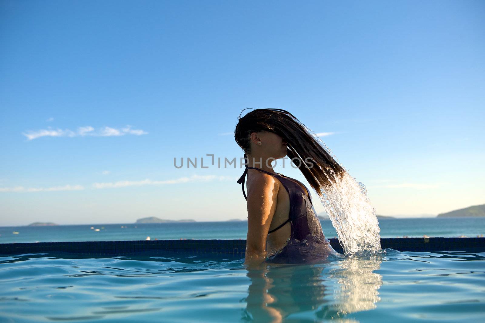 Woman relaxing on a swimming pool with a sea view in Buzios, Rio de Janeiro, Brazil