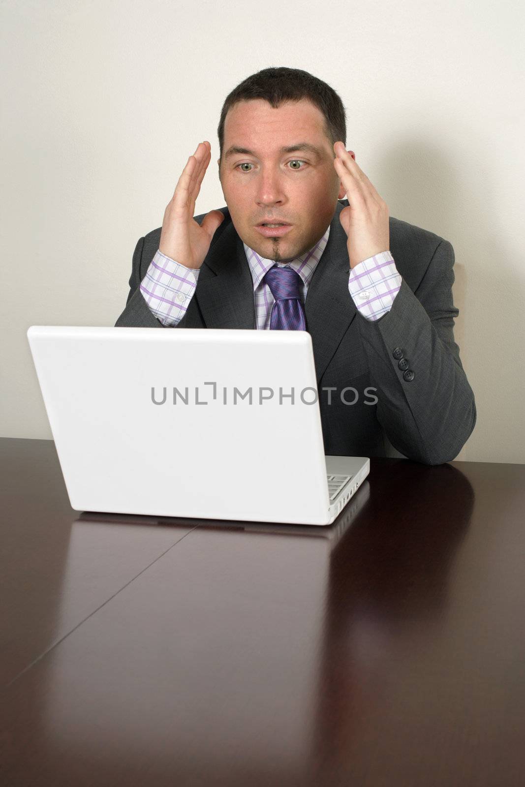 Shocked businessman in his thirties looking at a bad thing on his laptop.

