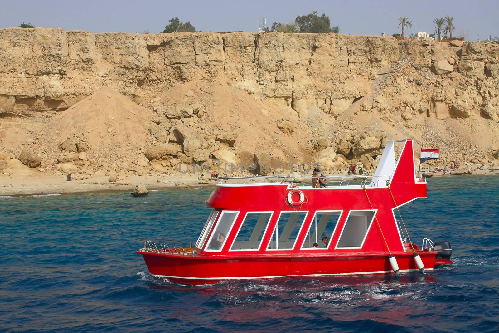 Little red boat floats for walking along the seashore.