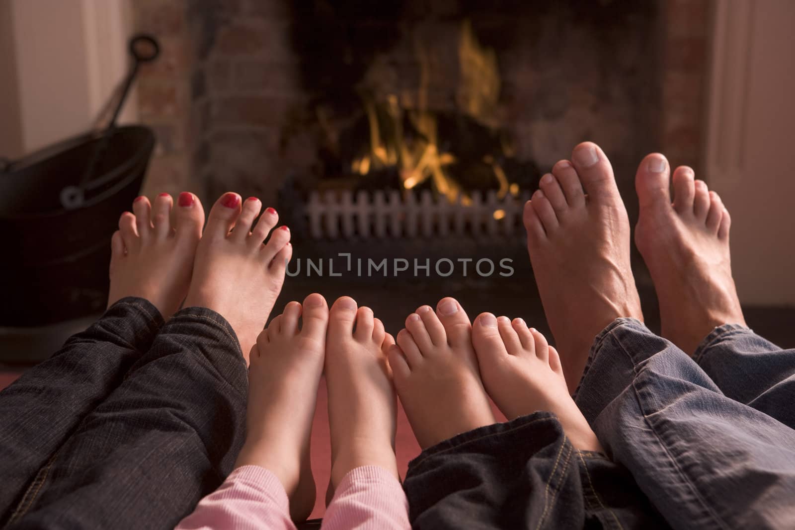 Family of feet warming at a fireplace by MonkeyBusiness