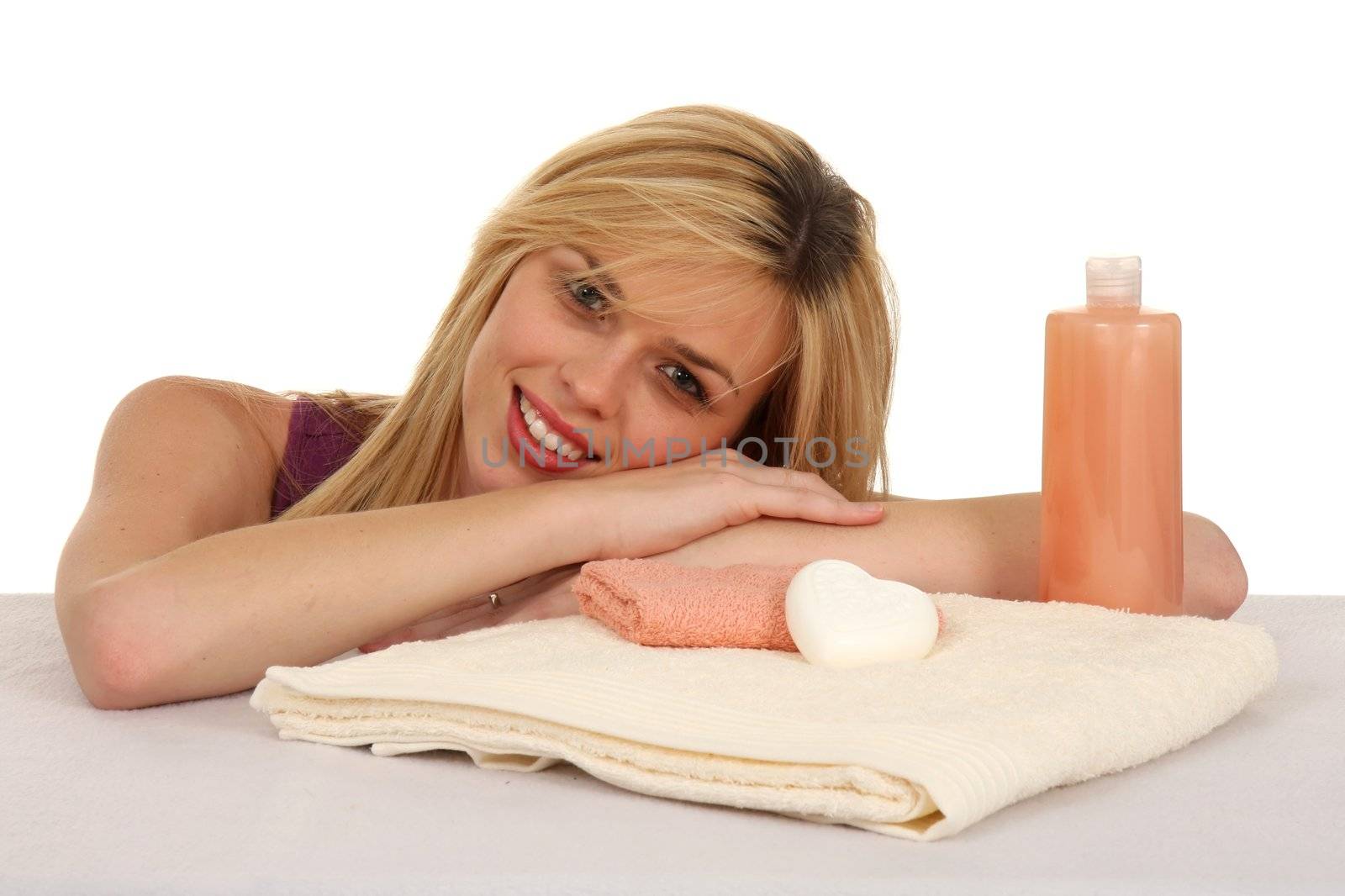 Attractive smiling blond girl with spa towels and soaps