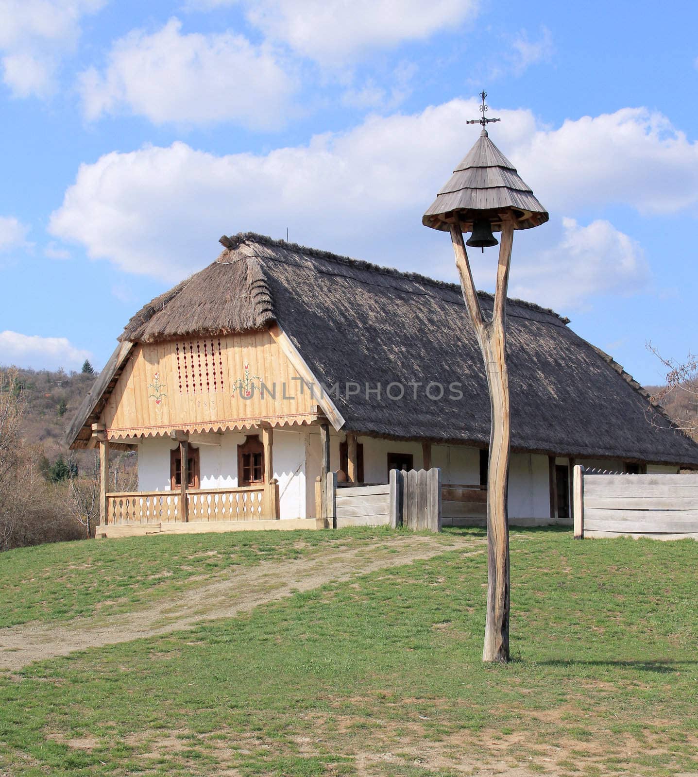 Rural thatched roof houses and a bell.