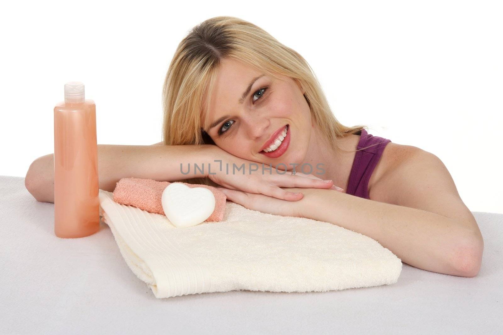 Attractive smiling blond girl with spa towels and soaps