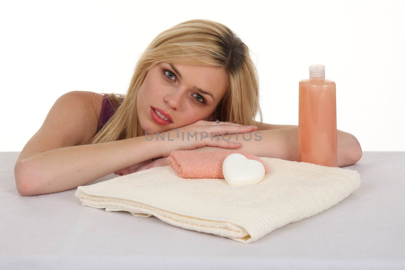 Attractive smiling blond girl with spa towels and soaps