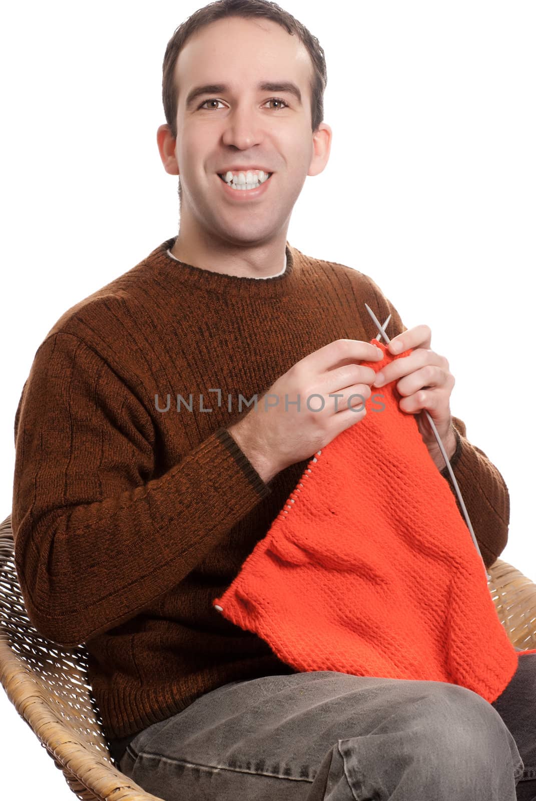 A happy man is knitting something while sitting down, isolated against a white background